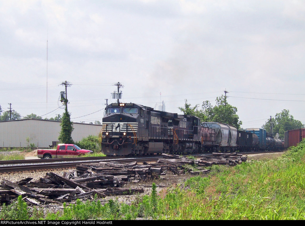 NS 9358 leads a train northbound past an empty woodchip train